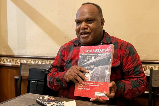 
					Bertus Asso menunjukkan buku “Huruf Bung Karno” untuk generasi Papua.  (KabarPapua.co/Natalya Yoku)