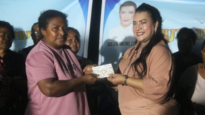 
					Anggota MRP Pokja Perempuan, Febiola Iriani Ohei menyerahkan buku tabungan Bank Papua kepada salah satu pedagang di Pasar Pharaa Sentani. (KabarPapua.co/Alan Youwe)