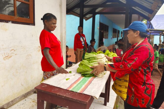 
					Sekda Kepulauan Yapen, Erny Tania membeli sayur masyarakat lokal saat penggalangan dana pembangunan gereja di Ambaidiru. (Humas Pemkab Yapen)