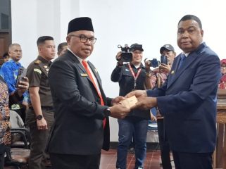 Bupati Kepulauan Yapen Benyamin Arisoy menyerahkan surat keputusan kepada Cyfrianus Y. Mambay usai pelantikan sebagai Penjabat Sekda Kepulauan Yapen. (KabarPapua.co/Ainun Faathirjal)
