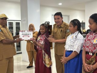 Plt Kepala Dinas Perpustakanaan dan Kearsipan Kabupaten Jayawijaya, Heribertus Mabel saat menyerahkan hadiah kepada Juara 1 Lomba Membaca Cerita Rakyat Papua. (Foto dok: Kominfo Jayawijaya)
