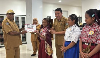 Plt Kepala Dinas Perpustakanaan dan Kearsipan Kabupaten Jayawijaya, Heribertus Mabel saat menyerahkan hadiah kepada Juara 1 Lomba Membaca Cerita Rakyat Papua. (Foto dok: Kominfo Jayawijaya)
