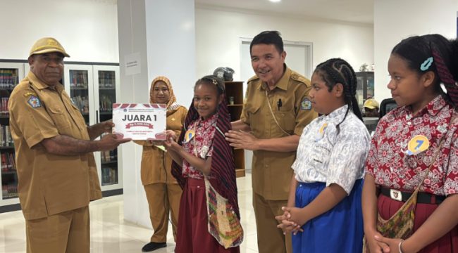 Plt Kepala Dinas Perpustakanaan dan Kearsipan Kabupaten Jayawijaya, Heribertus Mabel saat menyerahkan hadiah kepada Juara 1 Lomba Membaca Cerita Rakyat Papua. (Foto dok: Kominfo Jayawijaya)
