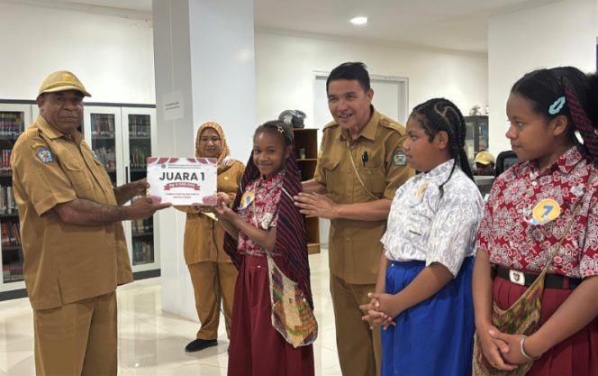 
					Plt Kepala Dinas Perpustakanaan dan Kearsipan Kabupaten Jayawijaya, Heribertus Mabel saat menyerahkan hadiah kepada Juara 1 Lomba Membaca Cerita Rakyat Papua. (Foto dok: Kominfo Jayawijaya)
