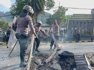 Pembersihan sisa pembakaran ban yang dilakukan oleh pendemo dari kampus USTJ. Foto: Humas Polresta Jayapura Kota