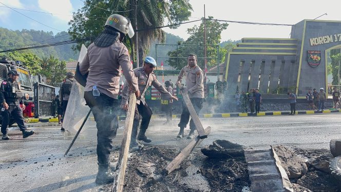 
					Pembersihan sisa pembakaran ban yang dilakukan oleh pendemo dari kampus USTJ. Foto: Humas Polresta Jayapura Kota