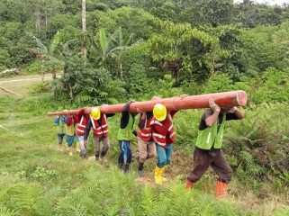 Petugas PLN bergotong royong mengangkut material tiang listrik melewati medan yang menantang demi mendukung pembangunan infrastruktur kelistrikan dan menghadirkan terang hingga ke pelosok Tanah Papua. Foto: PLN Papua 