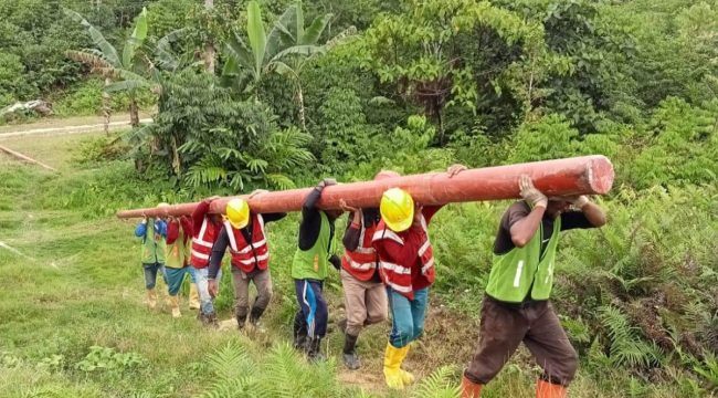 Petugas PLN bergotong royong mengangkut material tiang listrik melewati medan yang menantang demi mendukung pembangunan infrastruktur kelistrikan dan menghadirkan terang hingga ke pelosok Tanah Papua. Foto: PLN Papua 